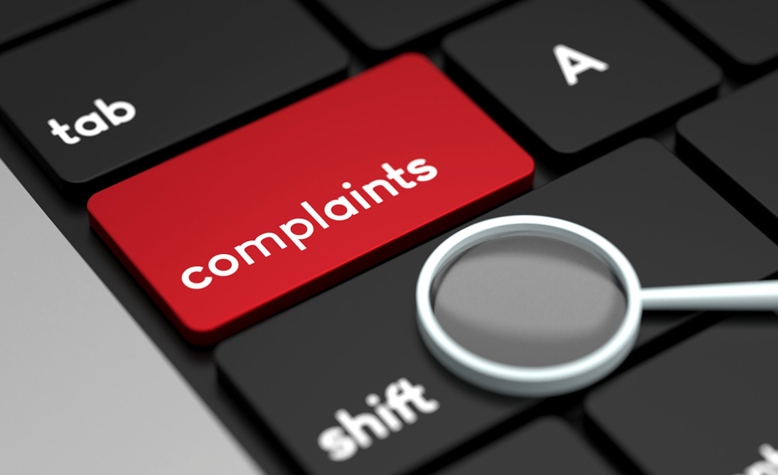 Photo: Black keyboard with the word "complaints" on a key highlighted in red. 