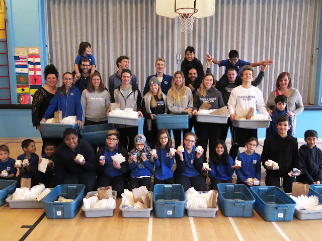 a group of students holding blue bins