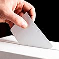 person putting a ballot into a voting box