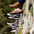 feet of teenagers sitting on mossy wall