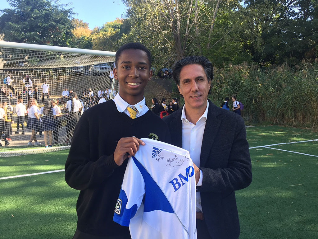 Mauro Biello and a student holding a t-shirt