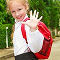 Young girl waving with backpack on