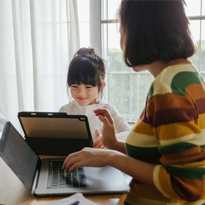 mother and daughter on laptops at their kitchen table learning and working together at home