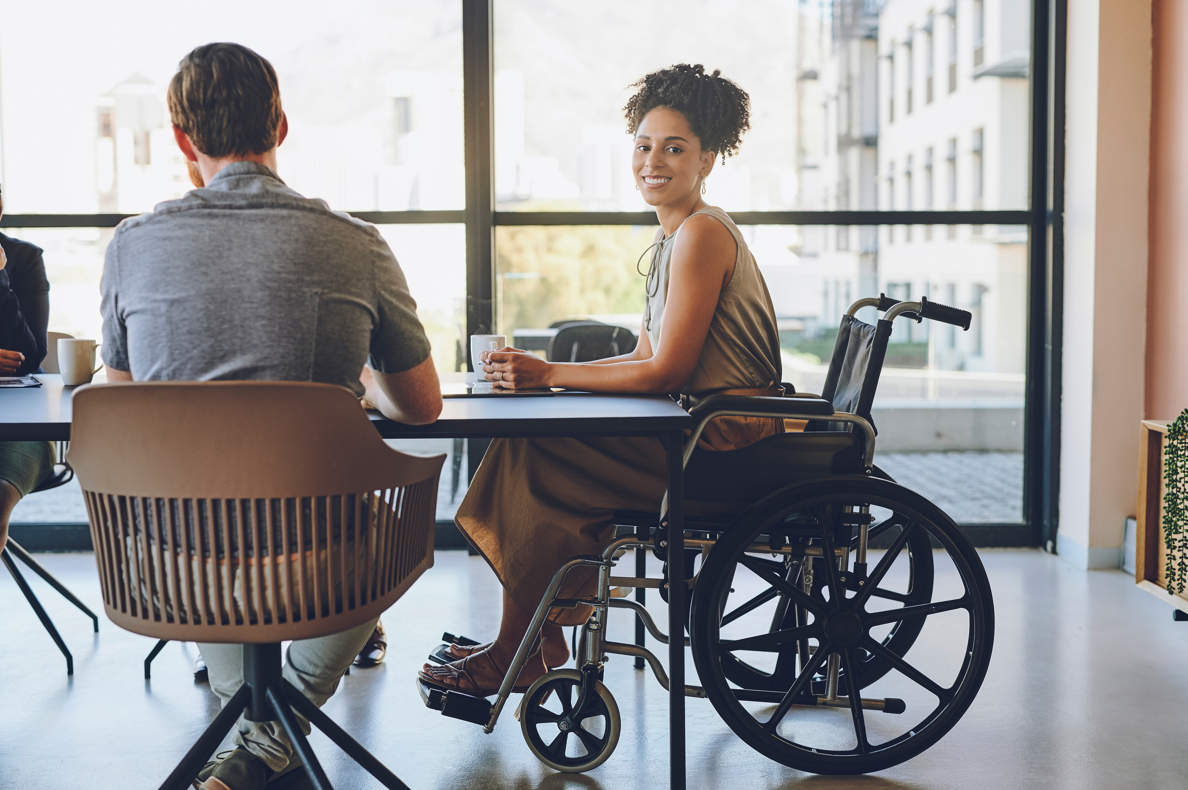 Business woman with disability in wheelchair in meeting at work, 